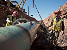 Workers remove a large clamp from a section of pipe during construction of part of the Keystone XL pipeline, in Prague, Oklahoma, U.S., on Monday, March 11, 2013, prior to the pipeline's previous cancellation.