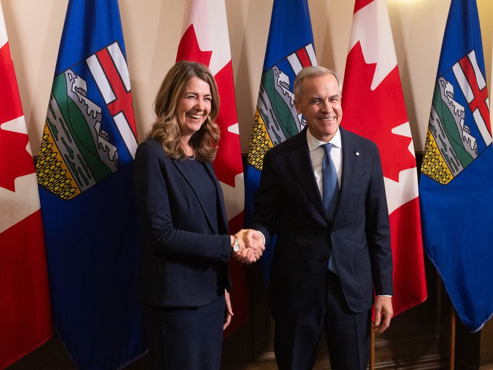 Prime Minister Mark Carney and Alberta Premier Danielle Smith shake hands in Calgary on Friday, May 15, 2026 before signing an agreement on oil pipeline approvals and carbon pricing.