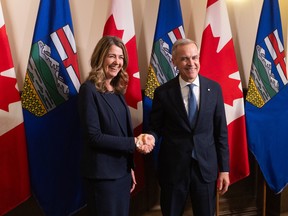 Prime Minister Mark Carney and Alberta Premier Danielle Smith shake hands in Calgary on Friday, May 15, 2026 before signing an agreement on oil pipeline approvals and carbon pricing.
