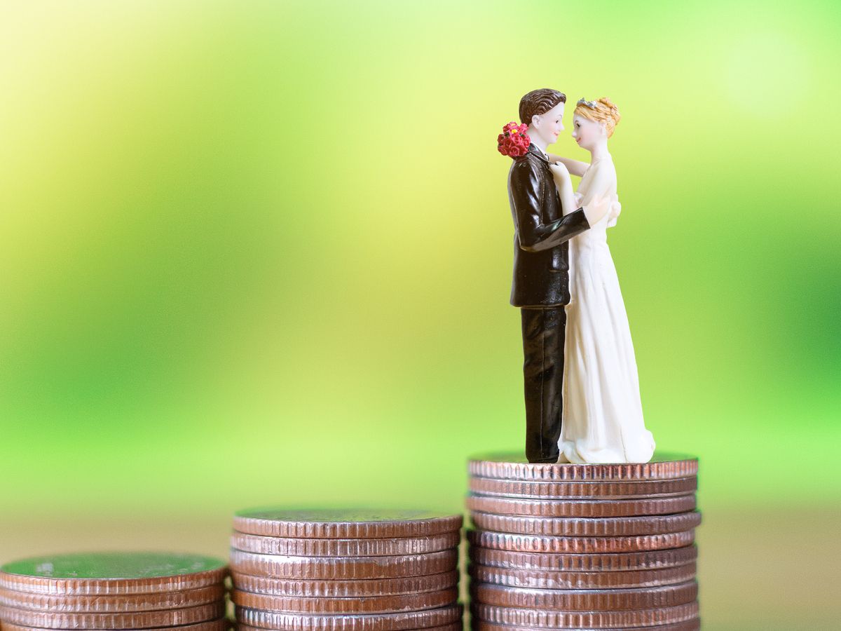 A plastic wedding couple embrace on top a pile of coins.