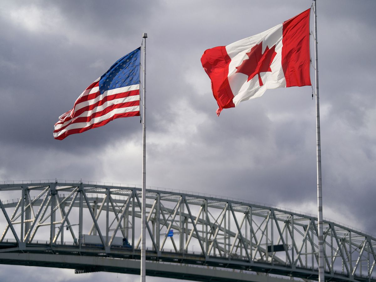 The U.S. and Canada flags next to the Blue Water Bridge border crossing in Point Edward, Ont.