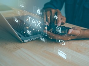 A man at a laptop and smartphone automatically files his taxes.