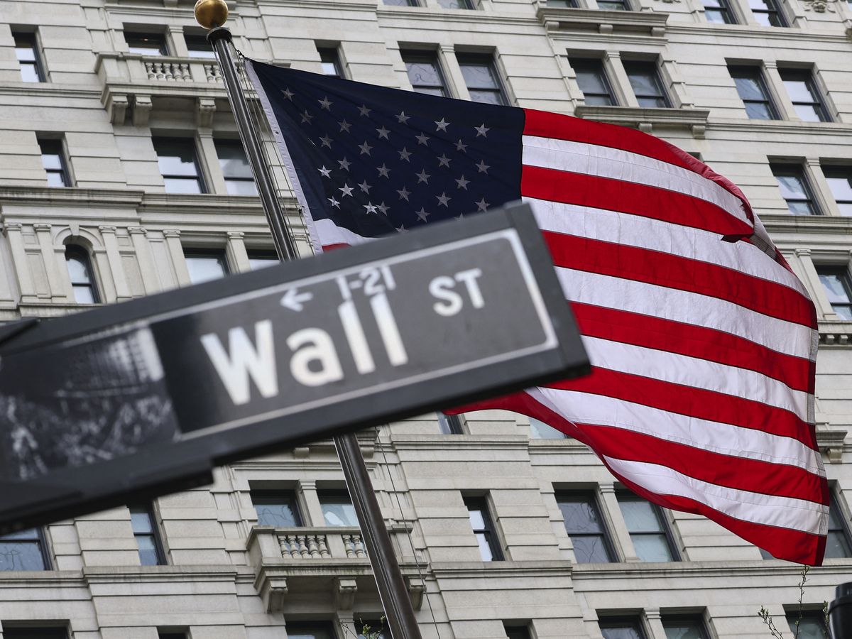 The American flag flies behind a Wall Street sign near the New York Stock Exchange (NYSE) in New York City on April 22, 2026