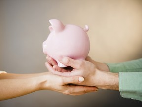 Close up of man's and woman's hands holding piggy bank, studio shot
