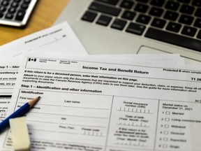 The canadian income tax and benefit return form with calculator, laptop and pen surrounding it.