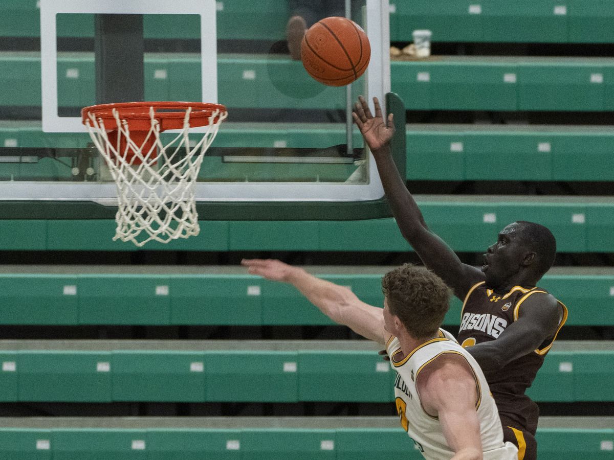 University of Manitoba Bisons, Manyang Tong floats the ball off the glass and in for a basket over University of Alberta Golden Bears Nate Waldron in Edmonton.