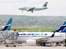 An Air Canada plane flies over a WestJet plane parked on the tarmac at the Calgary International Airport in this file photo from 2008.