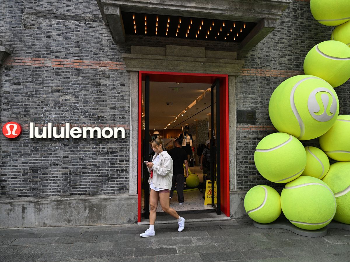 A woman walks on a street next to a Lululemon Athletica Inc. shop in Shanghai, China.