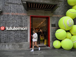 A woman walks on a street next to a Lululemon Athletica Inc. shop in Shanghai, China.
