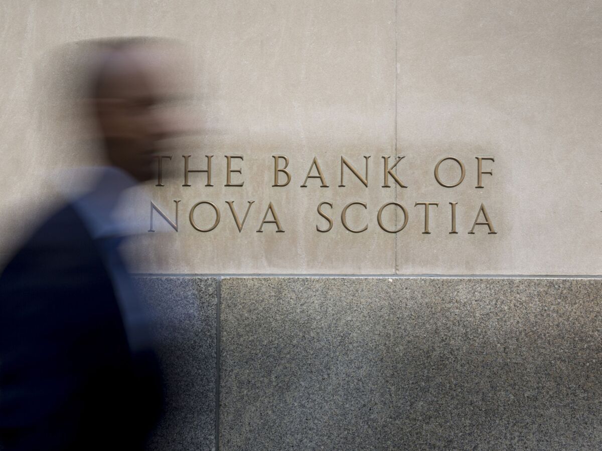 A commuter walks past signage displayed on the Bank of Nova Scotia (Scotiabank) in the financial district of Toronto, Ontario, Canada, on Thursday, July 7, 2016.