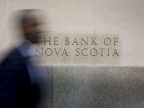 A commuter walks past signage displayed on the Bank of Nova Scotia (Scotiabank) in the financial district of Toronto, Ontario, Canada, on Thursday, July 7, 2016.