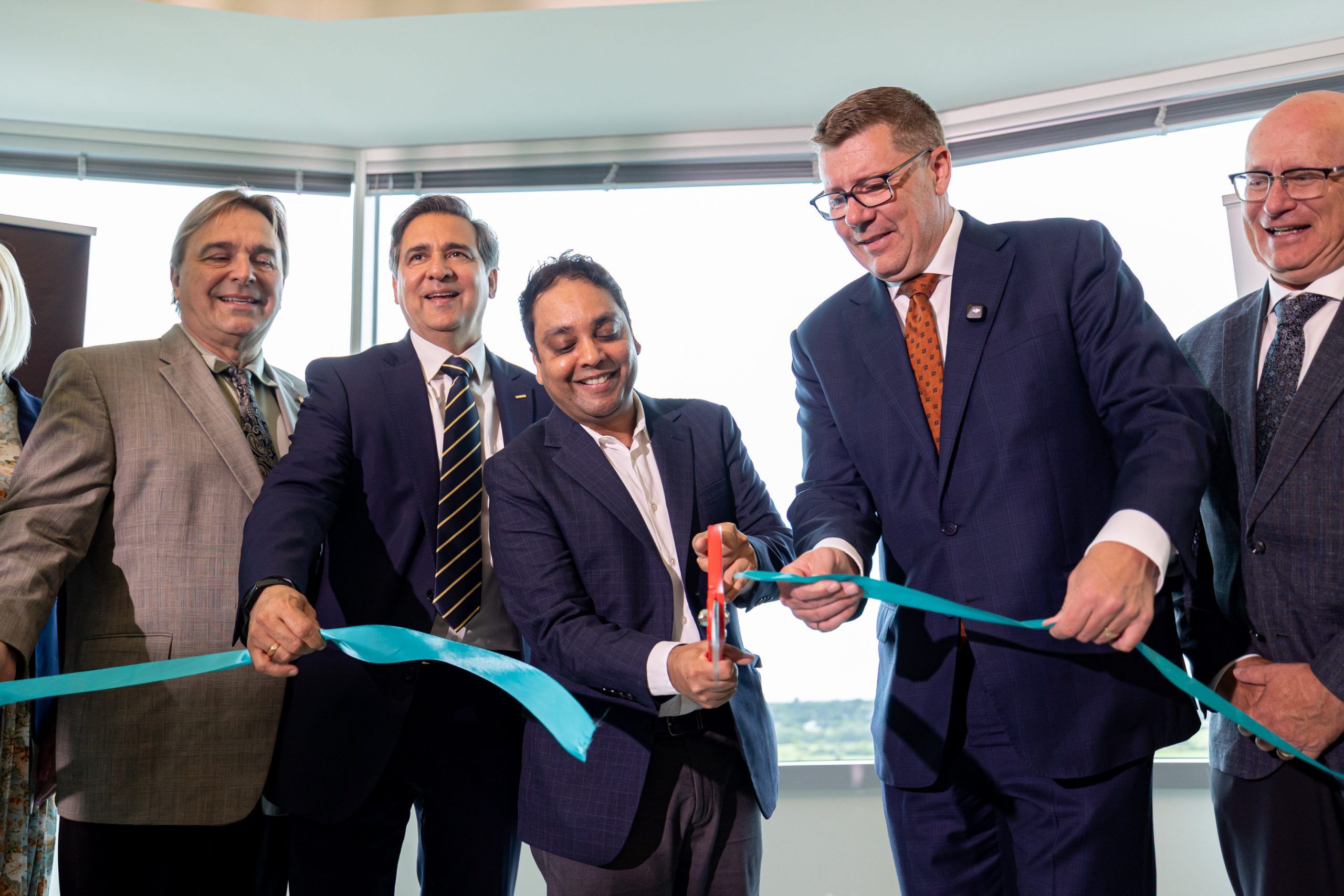 From left, Faisal Kazi, President and CEO of Siemens Canada, Amit Gupta, Chief AI Strategy Officer, SVP and GM of Siemens EDA, and Saskatchewan Premier Scott Moe take part in a ribbon-cutting ceremony during a Siemens Canada announcement in Saskatoon on Wednesday.