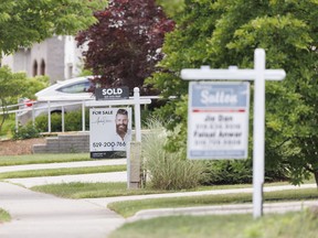 Real estate signs sit on lawns in London, Ont. on Tuesday, July 7, 2026.