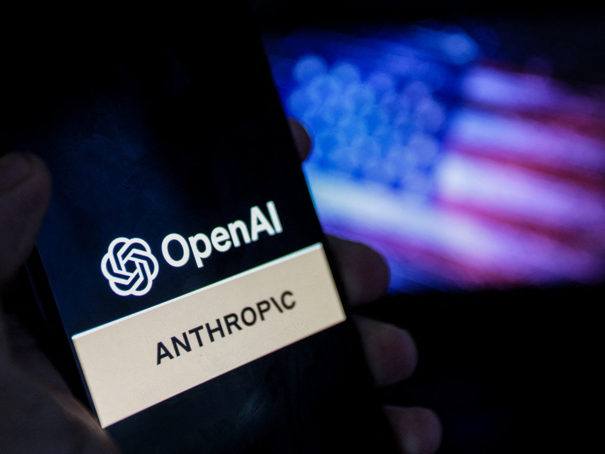 A smartphone screen displays the logos of OpenAI and Anthropic against a blurred backdrop of the American flag, symbolizing the intensifying competition in artificial intelligence between the two US-based companies in Tunis,Tunisia on June 17,2026.