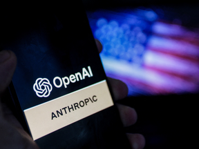 A smartphone screen displays the logos of OpenAI and Anthropic against a blurred backdrop of the American flag, symbolizing the intensifying competition in artificial intelligence between the two US-based companies in Tunis,Tunisia on June 17,2026.