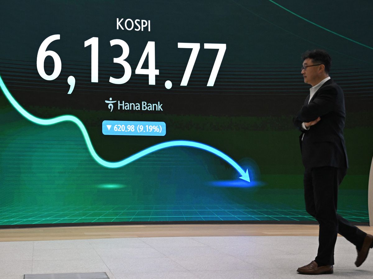 A man walks past an electronic screen showing South Korea's benchmark stock index (KOSPI) in a foreign exchange dealing room at the Hana Bank headquarters in Seoul on July 28, 2026.