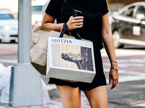 A pedestrian carries an Aritzia Inc. shopping bag while crossing a street in the Soho neighbourhood of New York.