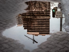 A condo tower under construction reflected in water on Wellesley Street West in Toronto, Ont.