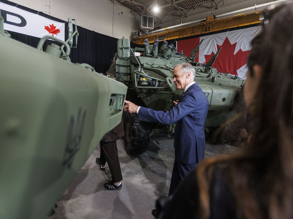 Prime Minister Mark Carney touches two light armoured vehicles as he leaves a press conference at General Dynamics Land Systems-Canada in London, Ont. on July 16, 2026.