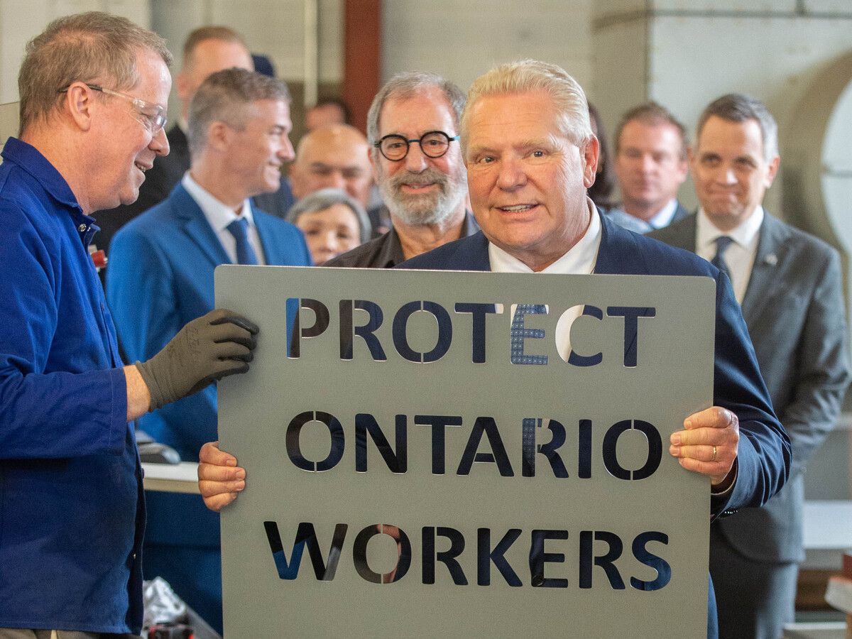Ontario Premier Leader Doug Ford holds up a piece of sheet metal with the words 'PROTECT ONTARIO WORKERS' cut into it at AMBICO Ltd., a manufacturer in Ottawa, Ont., on Feb. 4 2025.