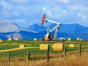 An oil and gas industry pumpjack drill rig in the Canadian Prairies with the Canadian Rockies in Alberta, Canada.