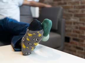 A closeup of the feet of a man, resting on a table, with mismatched socks