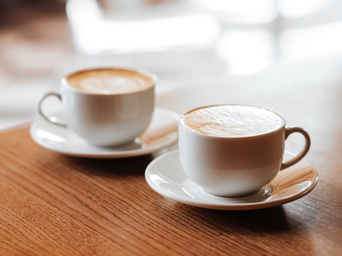 Two cups of cappuccino with latte art on wooden desktop