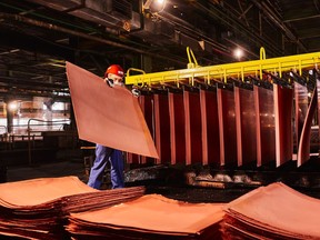 A worker handles newly formed copper cathode sheets in a warehouse at the KGHM Polska Miedz SA copper smelting plant in Glogow, Poland, on Tuesday, March 9, 2021.
