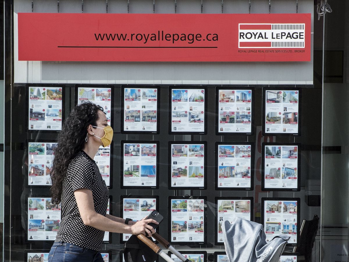 A pedestrian walks past real estate postings on Toronto’s Bloor Street West during the Covid 19 Pandemic, Thursday March 25, 2021.