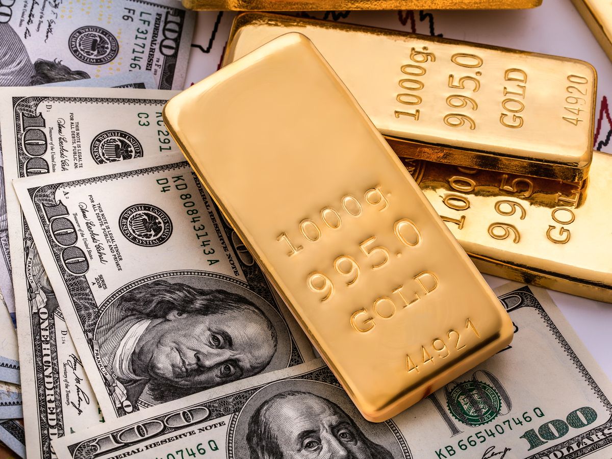 Gold bullions on hundred dollars banknotes and chart background.