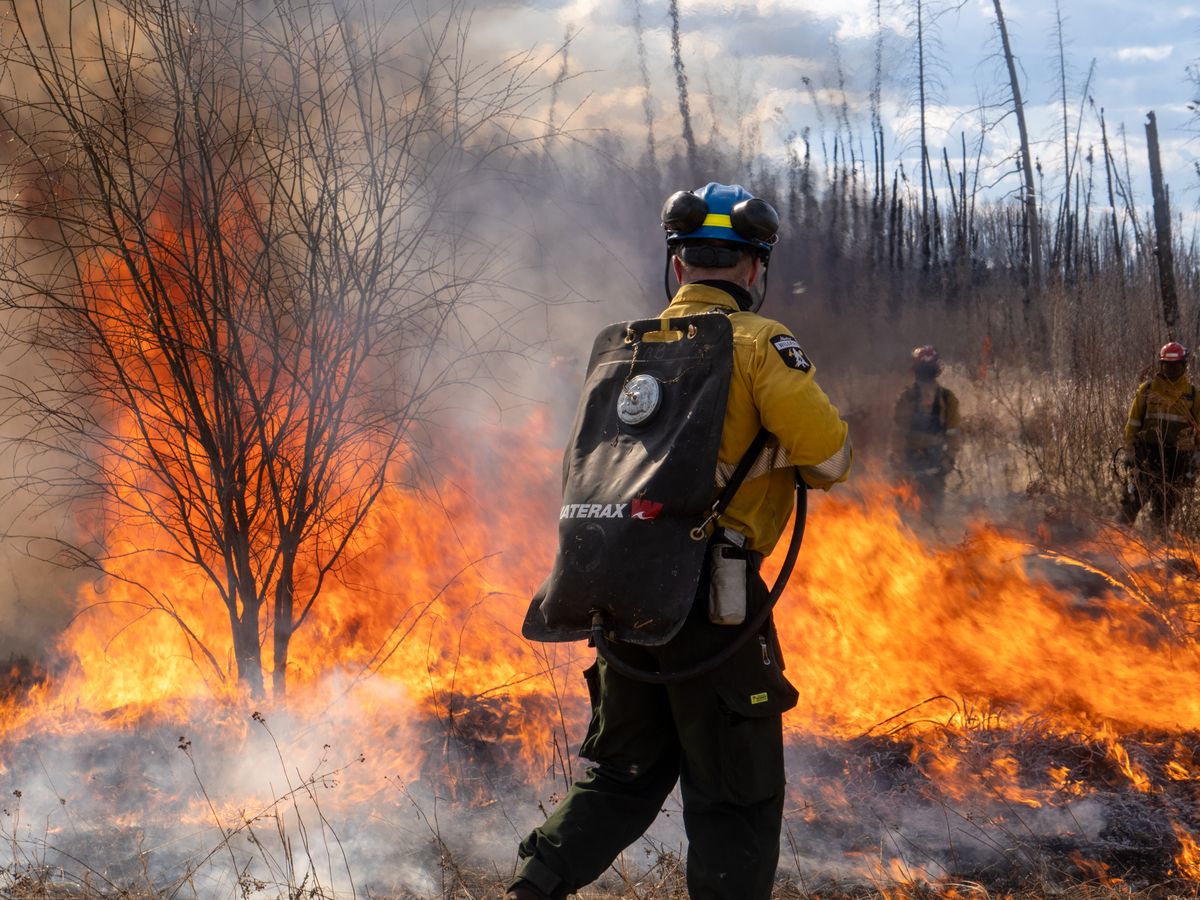 A firefighter from Alberta Wildfire douses controlled burns against wildfires near Saprae Creek south of Fort McMurray on April 24, 2025.