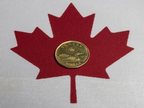 The Canadian loonie dollar and Canadian flag, Wednesday March 5, 2025.