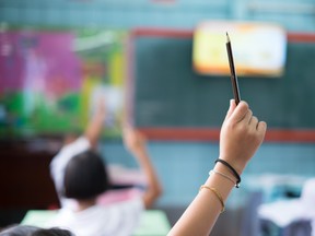 Student hands up asking a question in class at the elementary school.