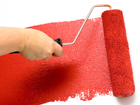 Paint roller painting bright red paint over white