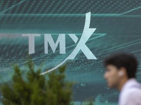 A pedestrian walks past TMX signage on Adelaide Street in Toronto’s Financial District, Tuesday July 29, 2025.