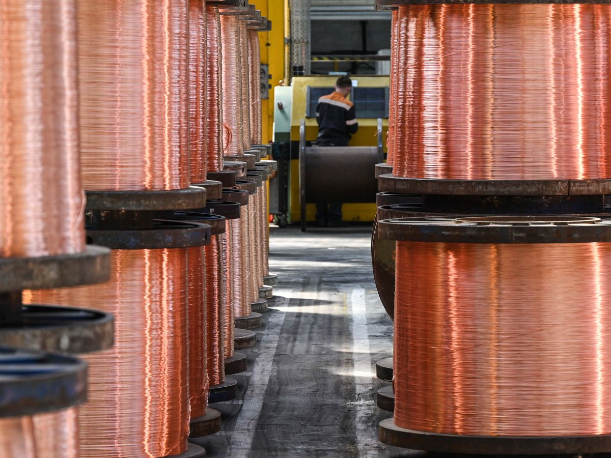 An employee works near rolls of copper wires at the Nexans manufacture in Lens, northern France, on May 11, 2022