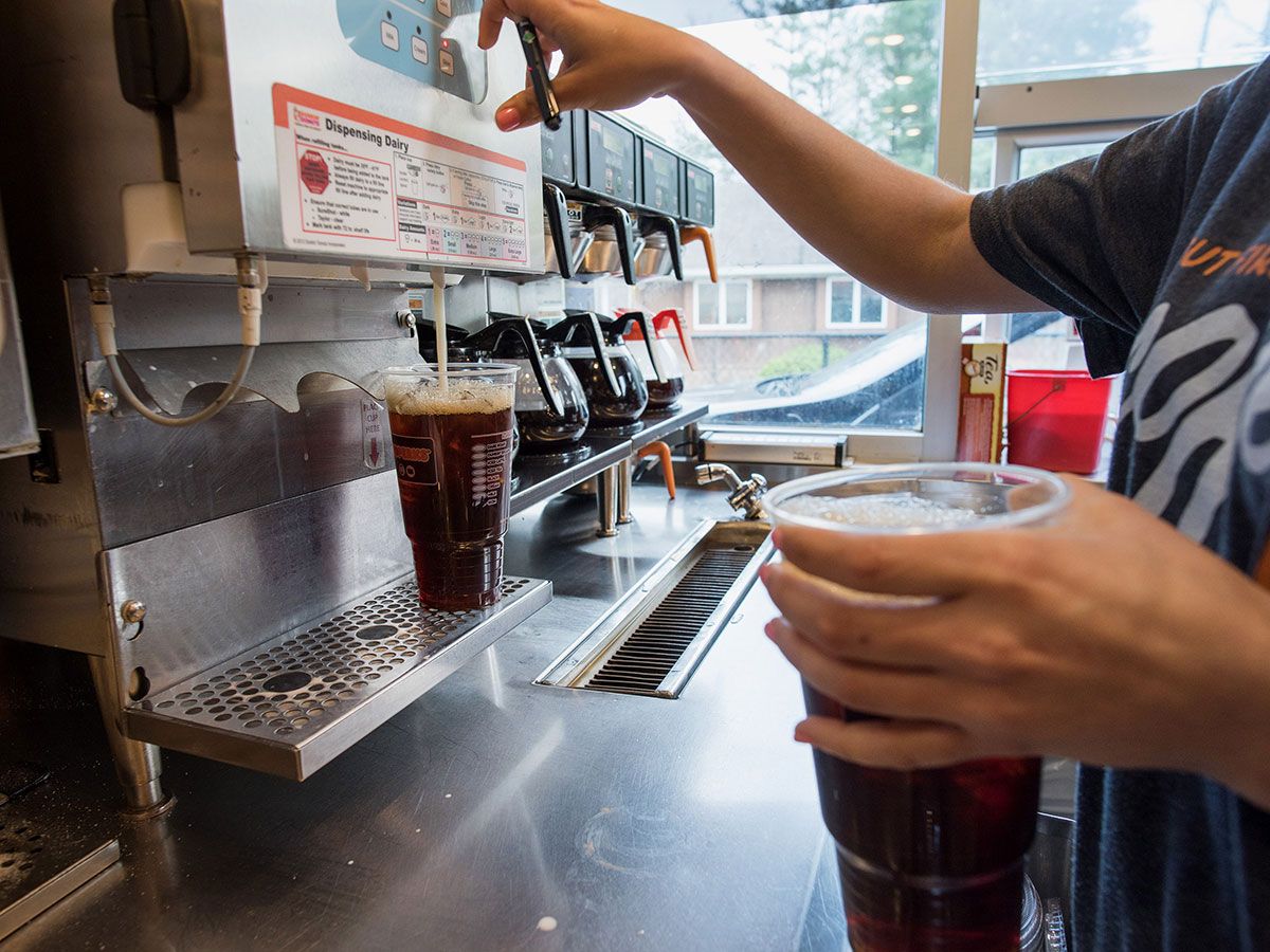 An employee fills a drinks order at a Dunkin' in New Jersey. The U.S. coffee chain will return to the Canadian market in late 2026 or early 2027, with plans to open hundreds of locations across the country.