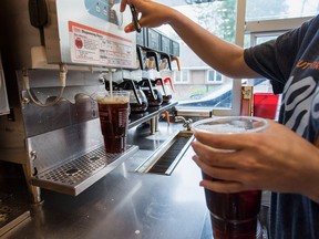 An employee fills a drinks order at a Dunkin' in New Jersey. The U.S. coffee chain will return to the Canadian market in late 2026 or early 2027, with plans to open hundreds of locations across the country.