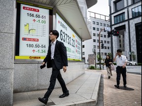 A man walks past a board showing the U.S. dollar and Japanese yen exchange rate at a securities firm in Tokyo on Aug. 3, 2026.