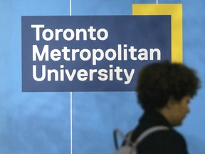 A pedestrian walks past Toronto Metropolitan University signage.