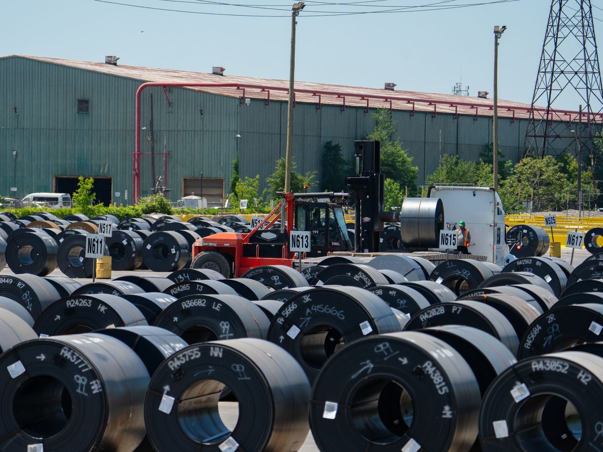 A heavy forklift operator places a coil of steel onto a flatbed truck at a ArcelorMittal Dofasco site in Hamilton, Ont.