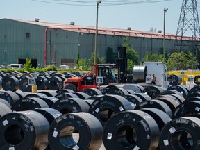 A heavy forklift operator places a coil of steel onto a flatbed truck at a ArcelorMittal Dofasco site in Hamilton, Ont.