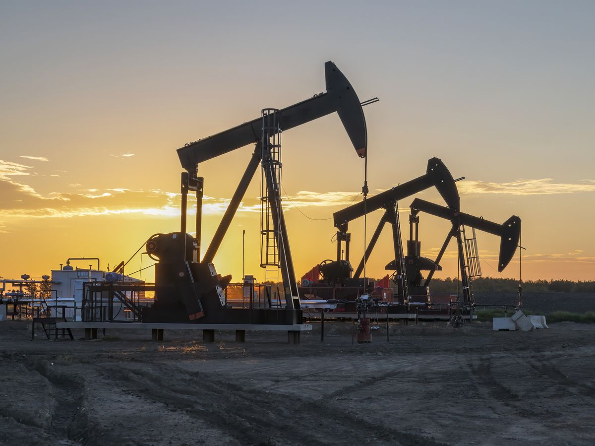 Three oil well pumpjacks at sunrise near Crossfield, Alberta, Canada