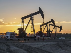 Three oil well pumpjacks at sunrise near Crossfield, Alberta, Canada
