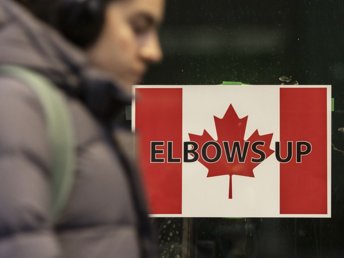 A person walks past “ELBOWS UP” signage with a Canadian flag on Toronto’s St. Clair Avenue West in reference to U.S. President Donald Trump taunting to Canada as the 51st state on April 11, 2025.