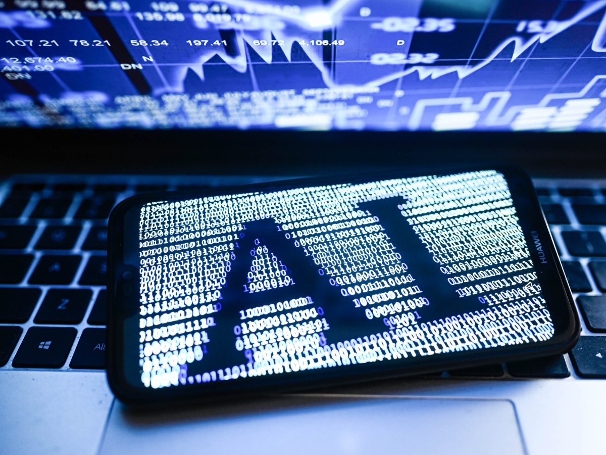 In this photo illustration an Artificial Intelligence (AI) symbol is displayed on a smartphone with stock market percentages in the background.