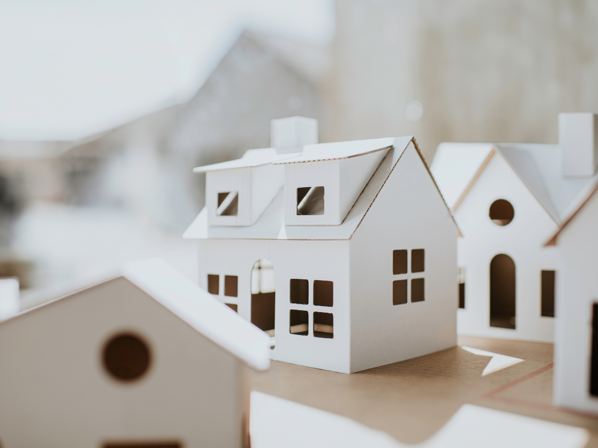 Conceptual and simple image of cardboard, white, plain houses in various shapes and sizes with space for copy.