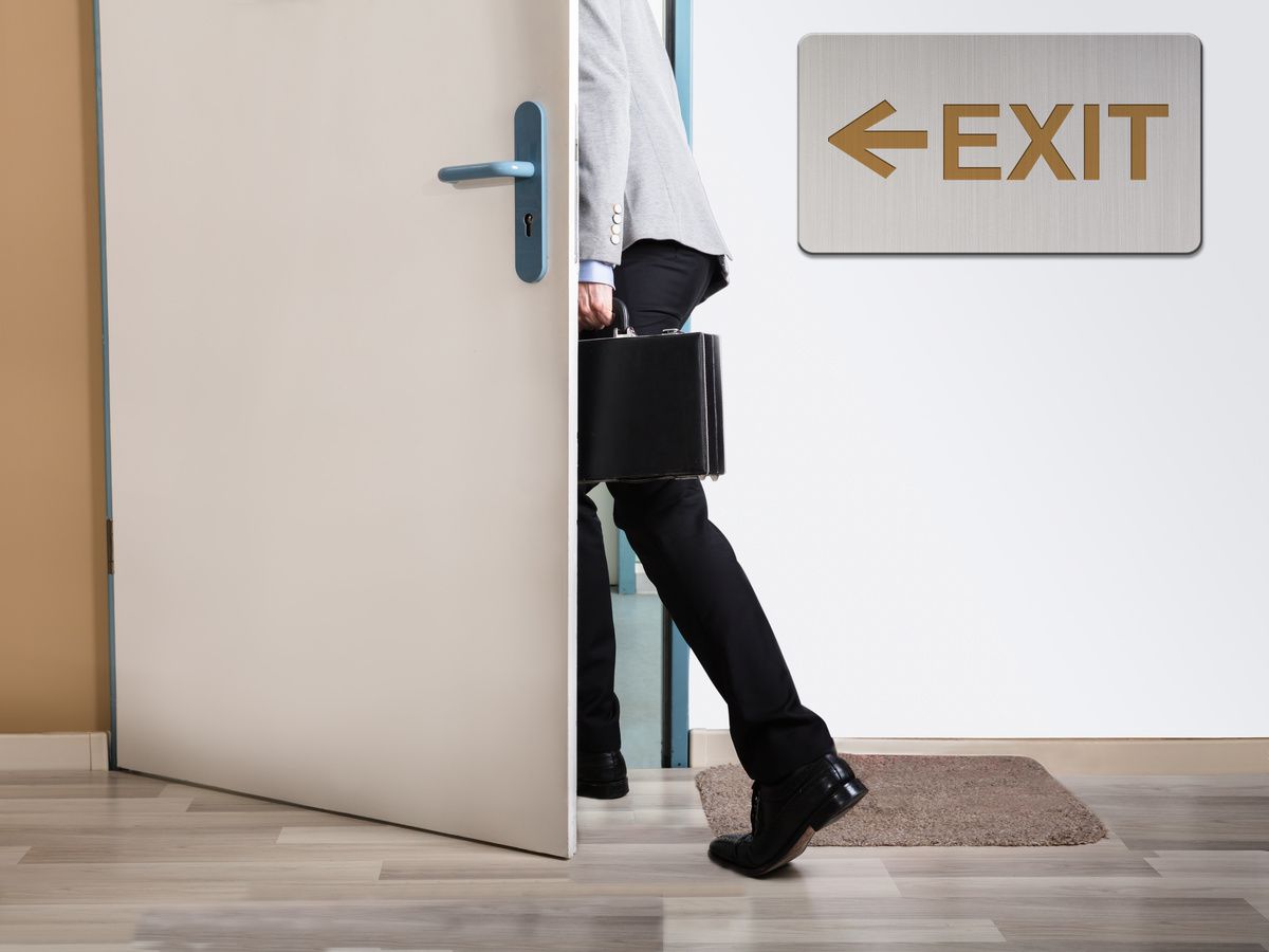 Businessperson Walking Out With Exit Sign On