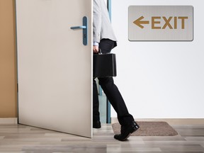 Businessperson Walking Out With Exit Sign On