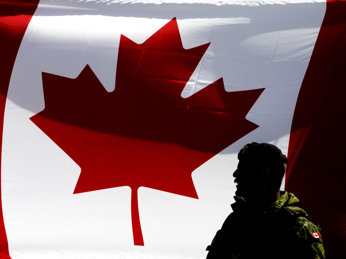 A soldier stands beside a Canadian flag as members of the military display vehicles and machinery at the 2026 Provincial Skills Canada Competition at the Edmonton Expo Centre on May 6, 2026.